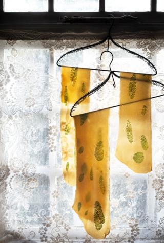 Sheets of pasta hanging to dry next to a window