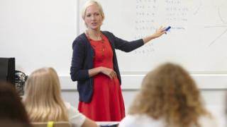 Teacher pointing to whiteboard (stock image)