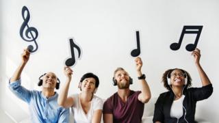 Personas agarrando notas musicales.