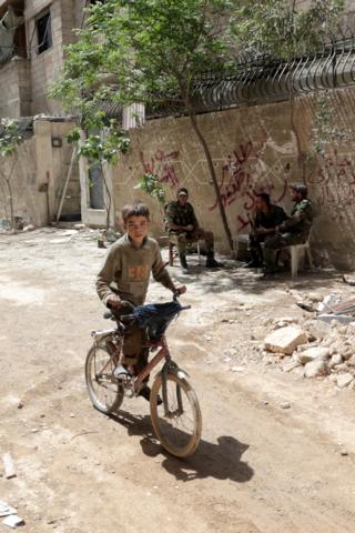 Boy rides bike in Syrian city