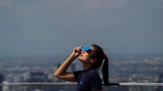A woman watches the eclipse in Bangkok