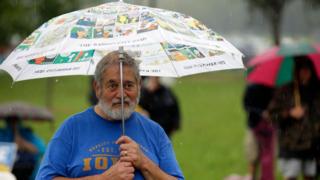 A man stands under an umbrella at Polk County Steak Fry