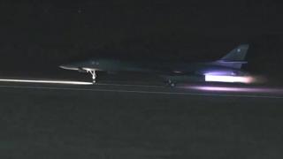 A B-1 bomber taking off from a runway in the dark