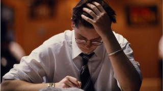 Joven se toma la cabeza mientras resuelve un examen