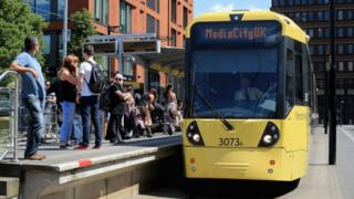 people wait next to tram at station