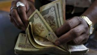 Денежный кредитор подсчитывает банкноты в индийской рупии в своем магазине в Ахмедабаде, Индия, на этом фото из архива от 6 мая 2015 года.