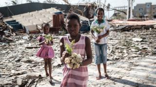 Girls collect artificial flowers from the rubble of a building destroyed by the cyclone Idai at Sacred Heart Catholic Church in Beira, Mozambique, on March 24, 2019.