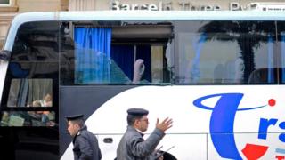 Egyptian police officers stand next to a tourist coach damaged in a gun attack close to the pyramids of Giza outside Cairo (7 January 2016)