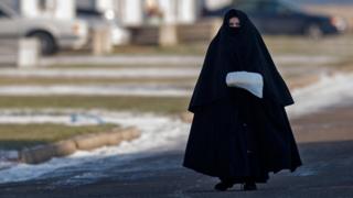 Mulher da comunidade Lev Tahor com sua característica roupa preta