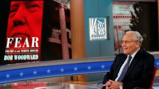 Боб Вудворд на фоне обложки своей книги "Страх: Трамп в Белом доме"