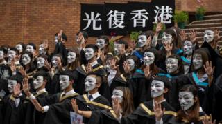 University-students-protest-by-covering-their-faces-with-masks-and-holding-a-free-Hong-Kong-signs
