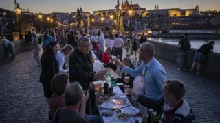 Residents dine at a long table set on the Charles Bridge