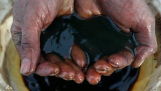 Crude oil pouring through a man's hand