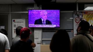 People watch a television broadcasting a speech by Chile's President Sebastian Pinera in an emergency room of a hospital amid anti-government protests in Santiago, Chile, 12 November, 2019