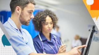 A male nurse checks the dosage on his digital tablet supervised by his staff nurse