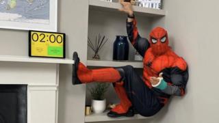 man-in-spiderman-costume-hanging-from-shelves