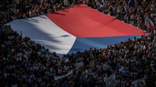 People carry a large Czech national flag as thousands of demonstrators gather to protest against Czech Prime Minister Andrej Babis on 4 June