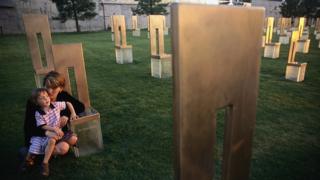 Aren Almon (in 2001) crouches with her daughter, Bella, at the memorial chair of her daughter, Baylee