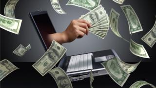 computadora y billetes de dólar