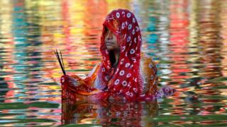 A Hindu woman stands in a lake