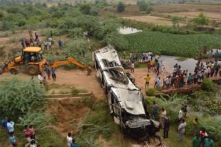 Onlookers and Indian police gather around the crumpled remains of a bus that crashed on the Delhi-Agra expressway, near Agra on July 8, 2019.