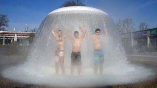 Visitors of the 'Sonnenbad' open-air public swimming pool take a shower at a water mushroom during the opening of the season on February 26, 2016 in Karlsruhe, southern Germany