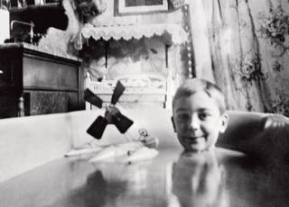 Jacques Henri Lartigue sits in a bath with a toy plane