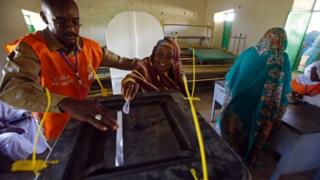 A woman casts her vote, with the help of an election official