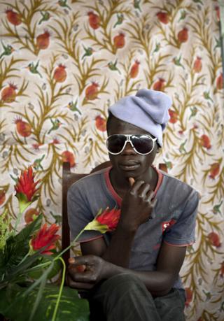 Boy in a beanie and sunglasses poses with flowers