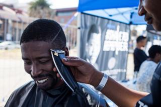 A youth has his haircut as part of the centenary celebrations of the birth of South Africa's first black leader Nelson Mandela following the theme "Be the Legacy", a call to action for all citizens of the world to live the values of "Madiba" a Xhosa title of respect for Mandela, in Johannesburg, on June 30, 2018. The Nelson Mandela Foundation launched with the Philips South Africa, the Shave to Remember campaign (#ShaveToRemember) which calls on people to honour the values embodied by the international icon Nelson Mandela by wearing his haircut. The first president of the "rainbow nation" Nelson Mandela was born on July 18, 1918 in Mvezo, Eastern Cape, and died December 5, 2013 in Johannesburg