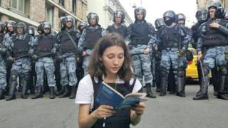 Olga Misik reads constitution as dozens of riot police stand behind her