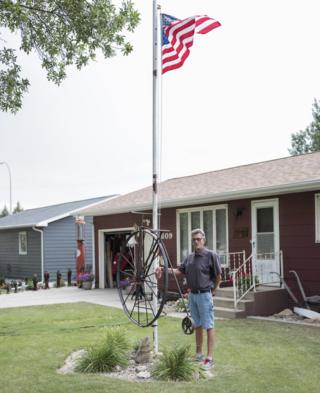 A man stands alongside a US flag