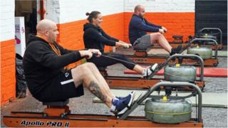 People using rowing machines outside a gym
