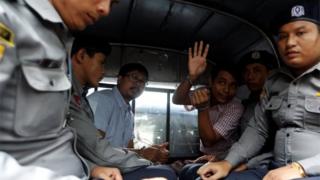 Detained Reuters journalist Wa Lone and Kyaw Soe Oo sit beside police officers as they leave Insein court in Yangon, Myanmar July 9, 2018.