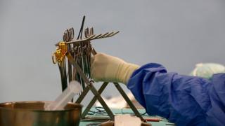 A doctor reaching for surgical instruments