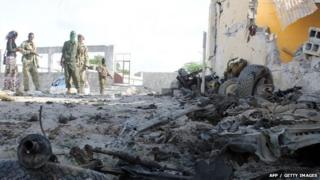 Somali soldiers stand next to the site where Al Shebab militants carried out a suicide attack against a military intelligence base in Mogadishu 21 June 2015