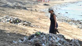 Tourist walks past rubbish on Kuta beach