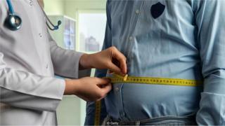 Médica mede cintura de paciente com fita métrica