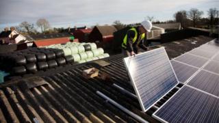 Человек кладет солнечные батареи на крышу