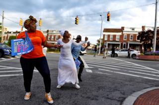 People dance in the street while holding placards reading 