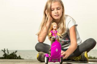 Молодая девушка играет с куклой на скутере в стиле сегвей