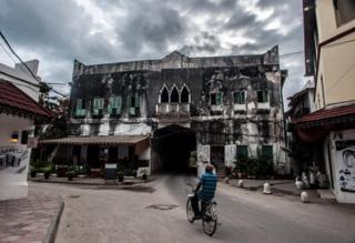 Mwanamume anapeleka baiskeli mjini Zanzibar