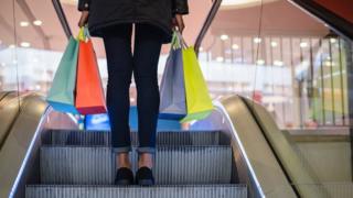 Shopper with four bags on an escalator