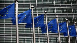 EU flags waving outside European Commission building in Brussels
