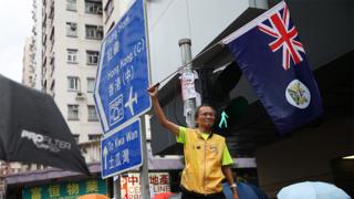 香港九龙参与“光复红土”游行一名年长男子挥舞旧英属香港旗帜(17/8/2019)