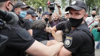 Ukrainian policemen detain a man during protests