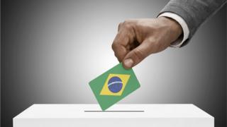 Mão segurando cédula no formato de bandeira