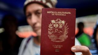 Una mujer venezolana muestra su pasaporte.