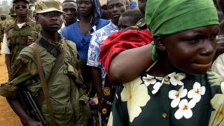 Des enfants soldats tiennent la foule en respect lors d'un meeting du chef de guerre Thomas Lubanga à Iga-Barrière en 2003.