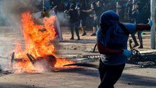 Manifestante devolviendo una bomba lacrimógena.